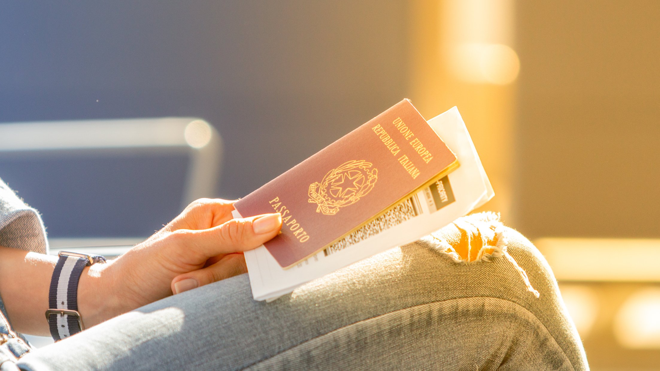 Italian passport and boarding pass in the hands of woman awaiting departure flight in waiting hall - concept of independence and easy traveling in Europe